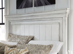 White panel bed headboard with vertical slat panels and beige patterned pillows.