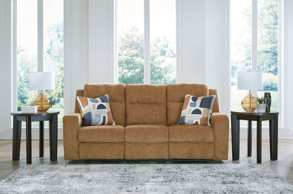 Honey reclining sofa with two patterned throw pillows, wide front view