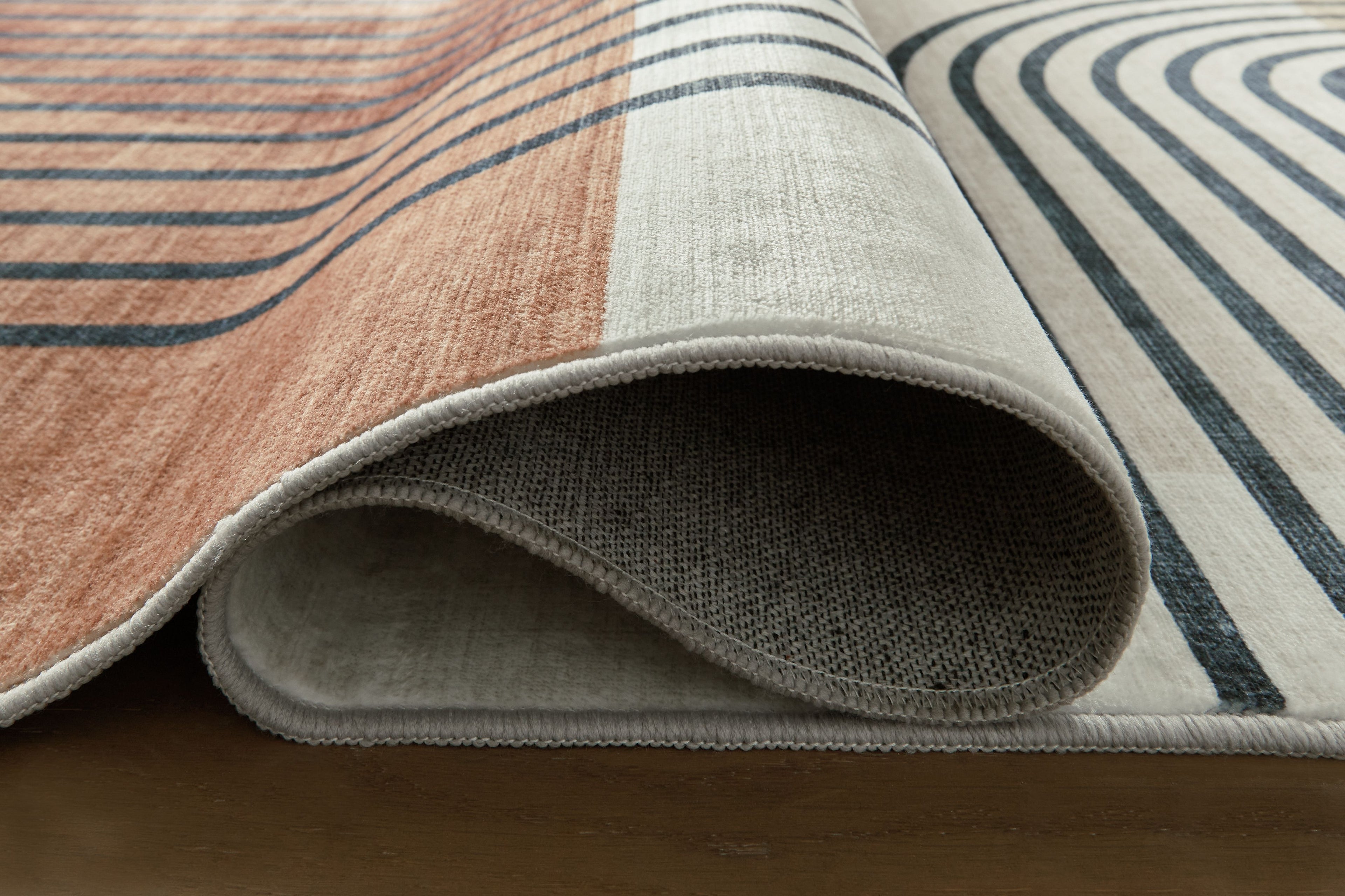 Farrendale washable rug, rolled edge view in beige and dark blue-gray with stripes
