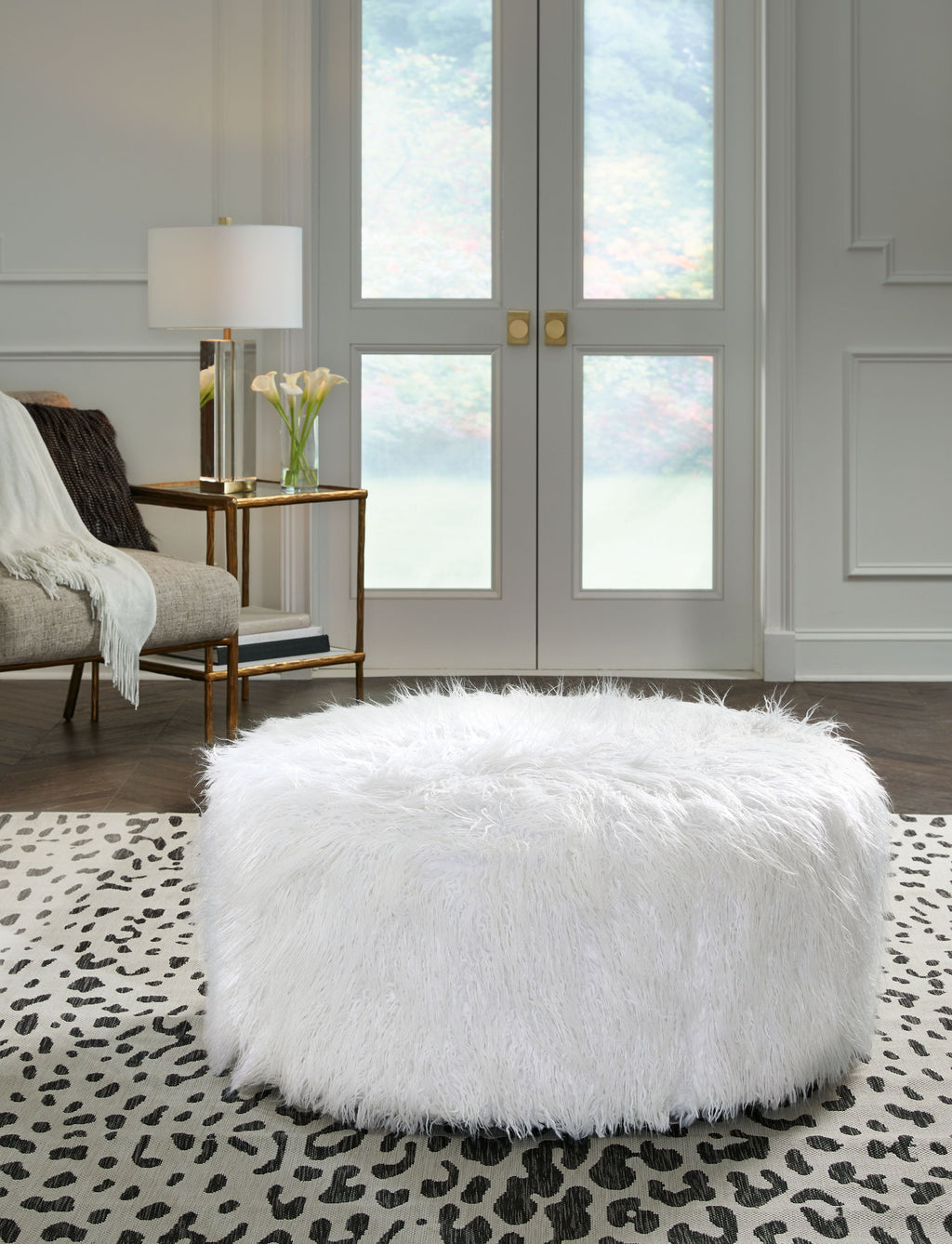 Oversized ottoman with shaggy white faux fur upholstery and rounded shape