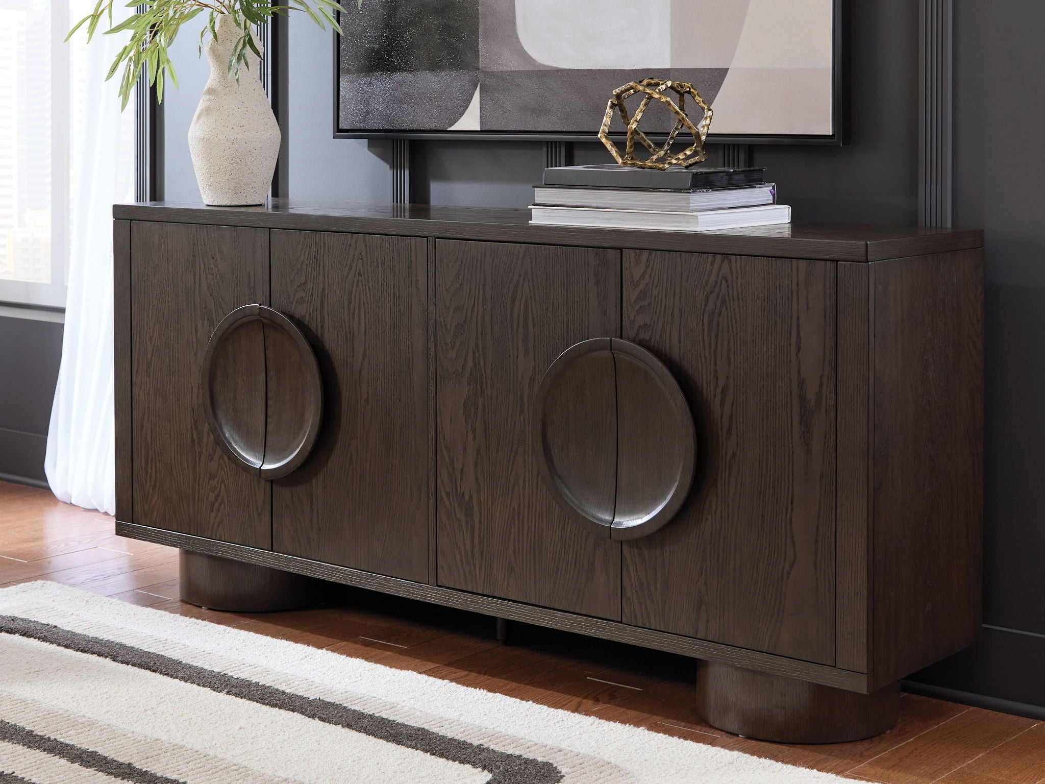 Dark brown accent cabinet with oval ring metal handles and four-panel door fronts