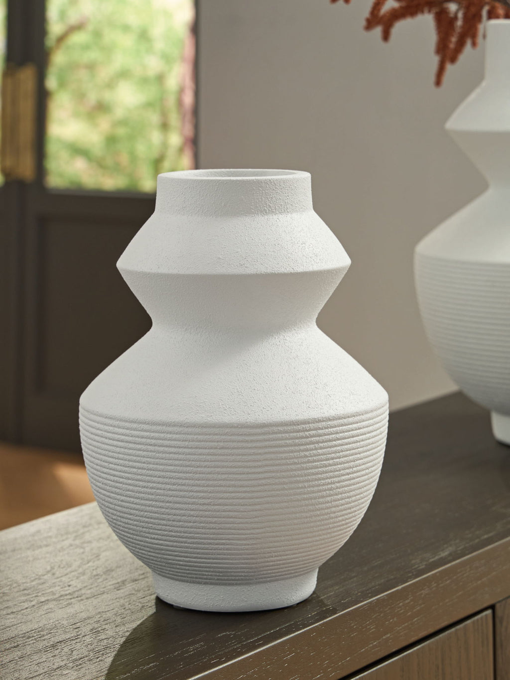 White ceramic vase with geometric silhouette and ribbed body, set on a table