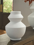 White ceramic vase with geometric silhouette and ribbed body, set on a table