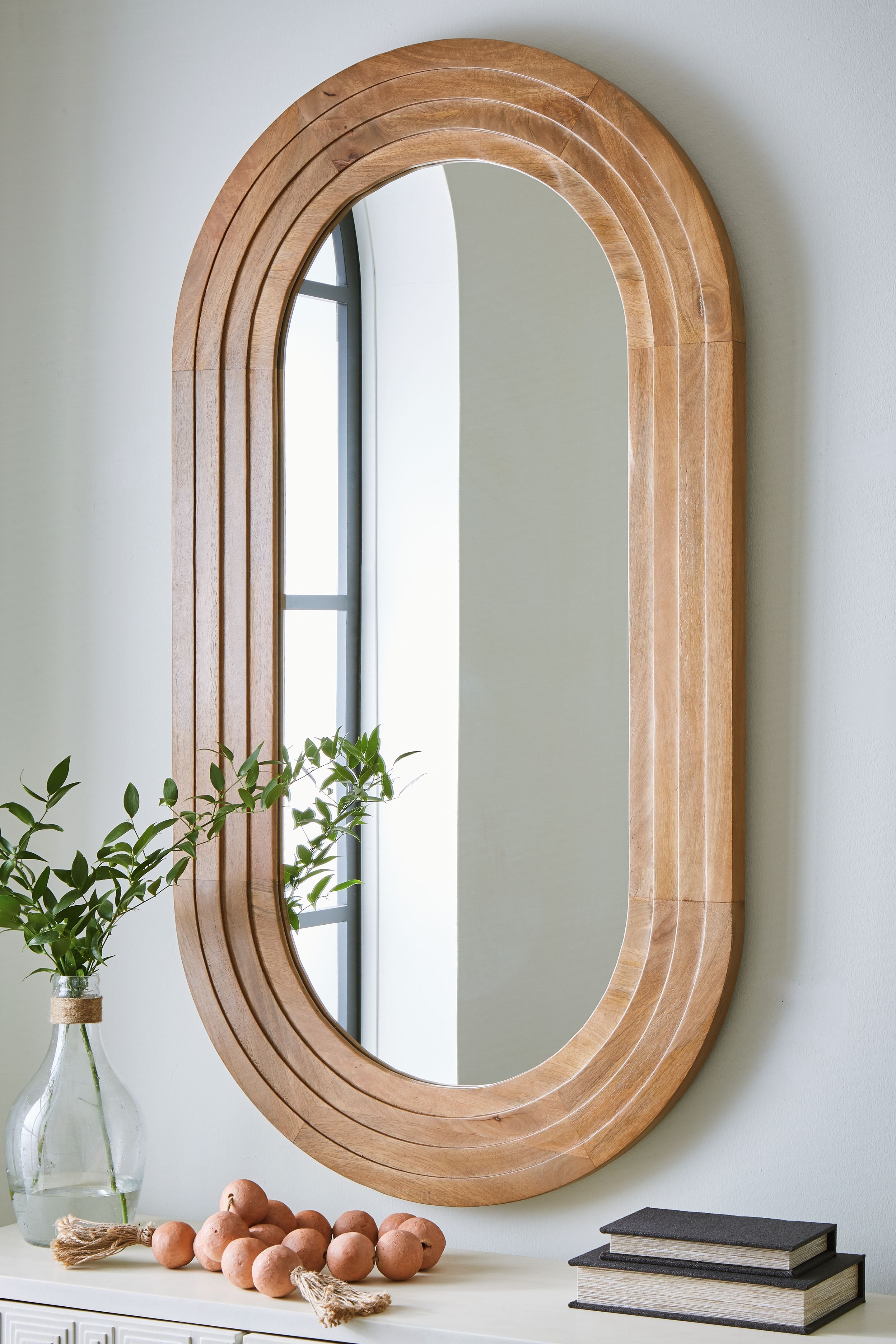 Brown oval accent mirror with layered wood frame and arched shape