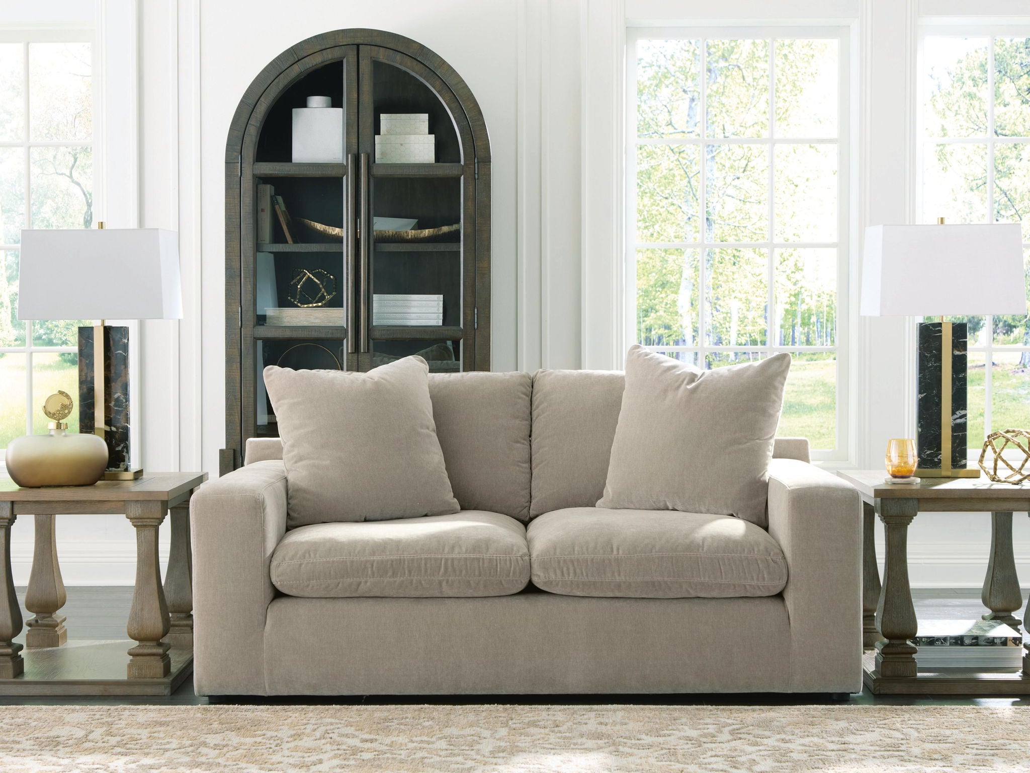 Gray loveseat with two seat cushions and four tall back pillows, low arms