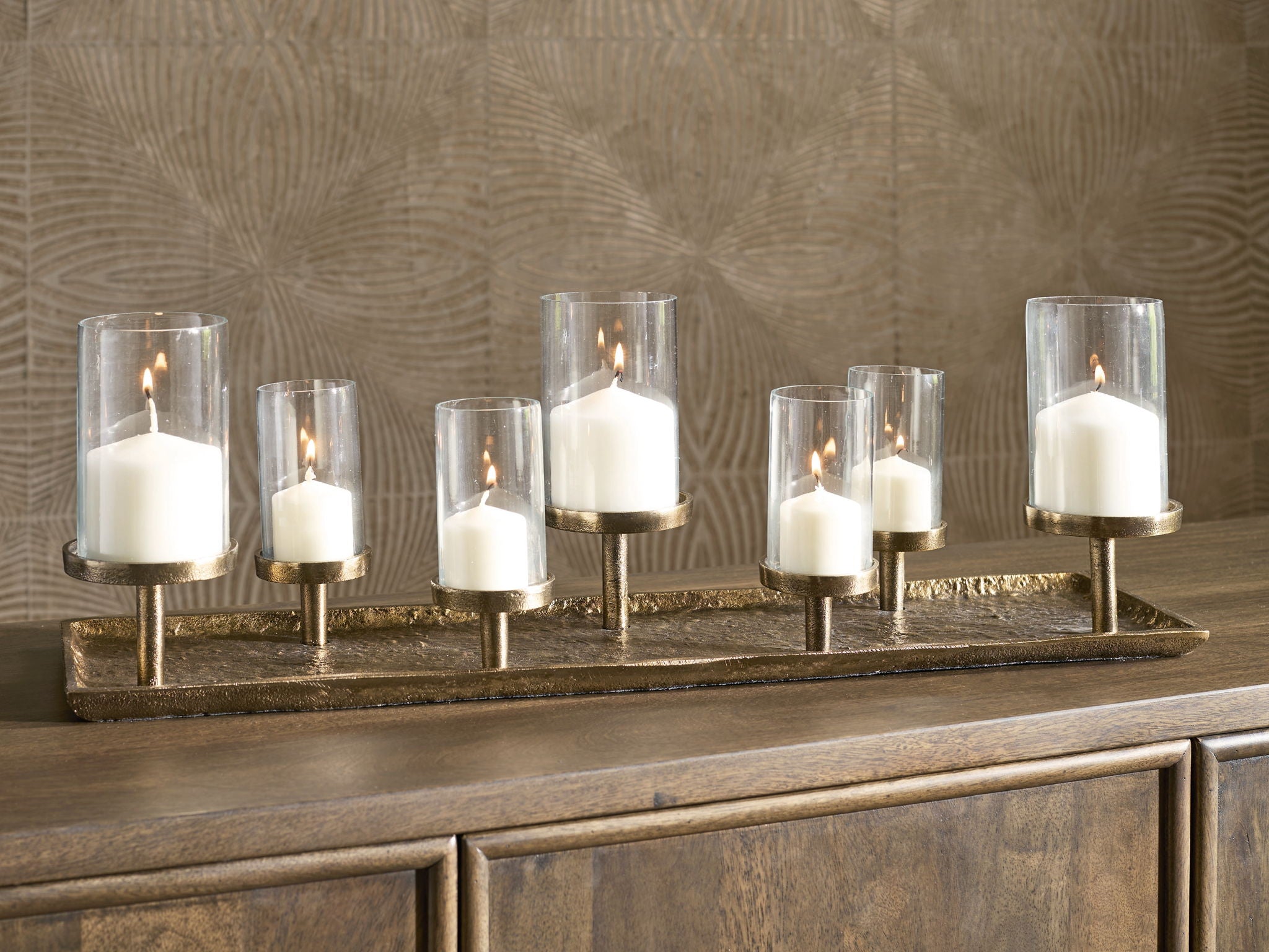 Antique brass candle holder with six lit candles and clear glass cylinders