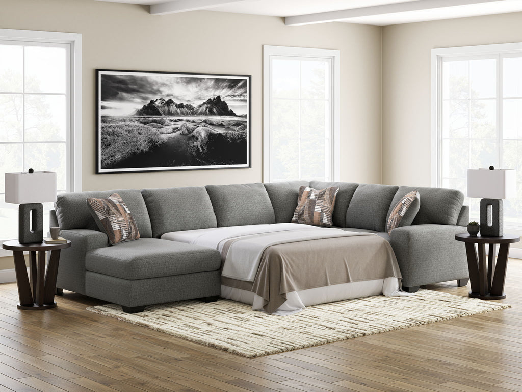 Gray sectional sleeper sofa with chaise, white bed cover, and accent throw pillows