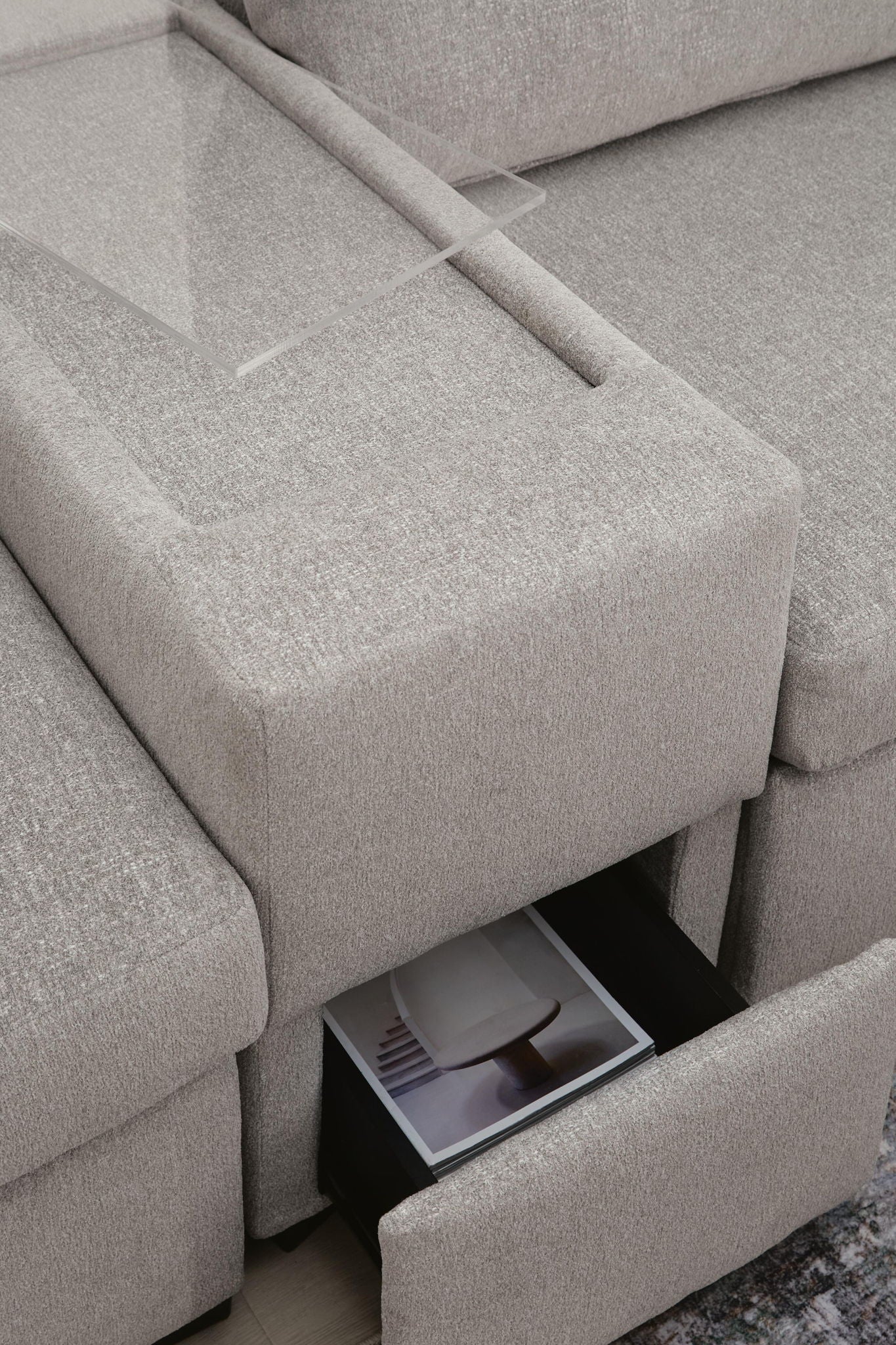 Gray sectional sofa arm area with open storage compartment beneath the seat cushion