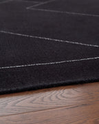 Black rug edge close-up showing low-pile texture and thin white border lines