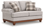 Upholstered loveseat with two front cushions, rolled arms, and plaid pillows in sand