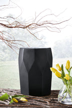 Black geometric stool with carved side panels and octagonal top.