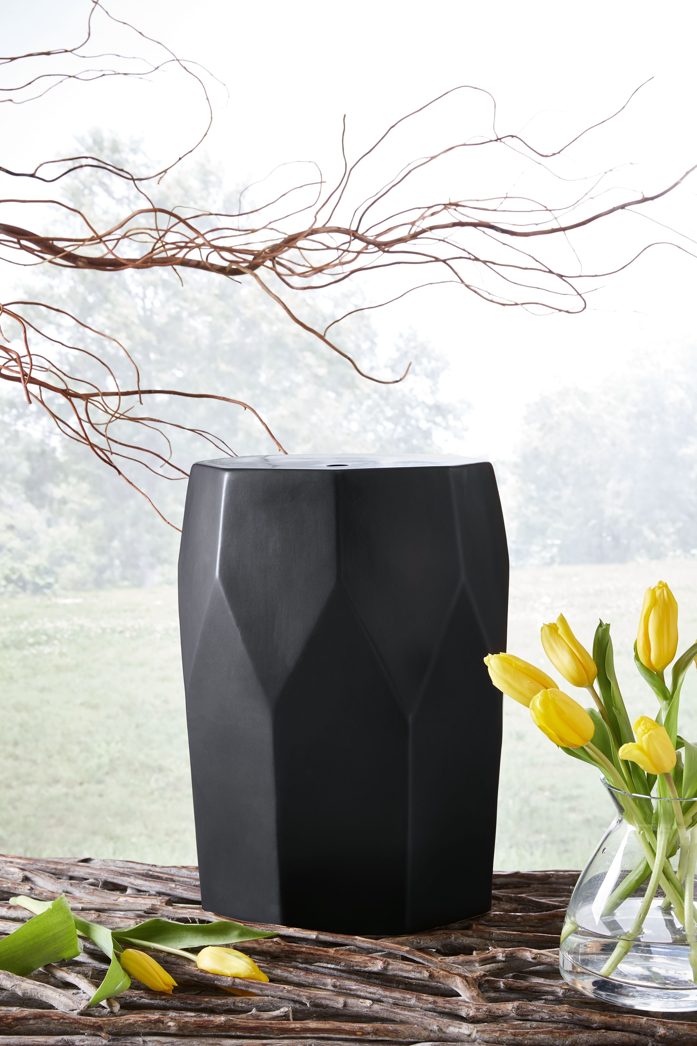 Black geometric stool with carved side panels and octagonal top.