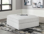 Oversized accent ottoman with light gray ribbed upholstery, square cushioned top