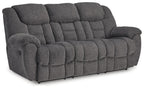 Dark gray reclining sofa with tufted back and padded arms, deep cushioned seat