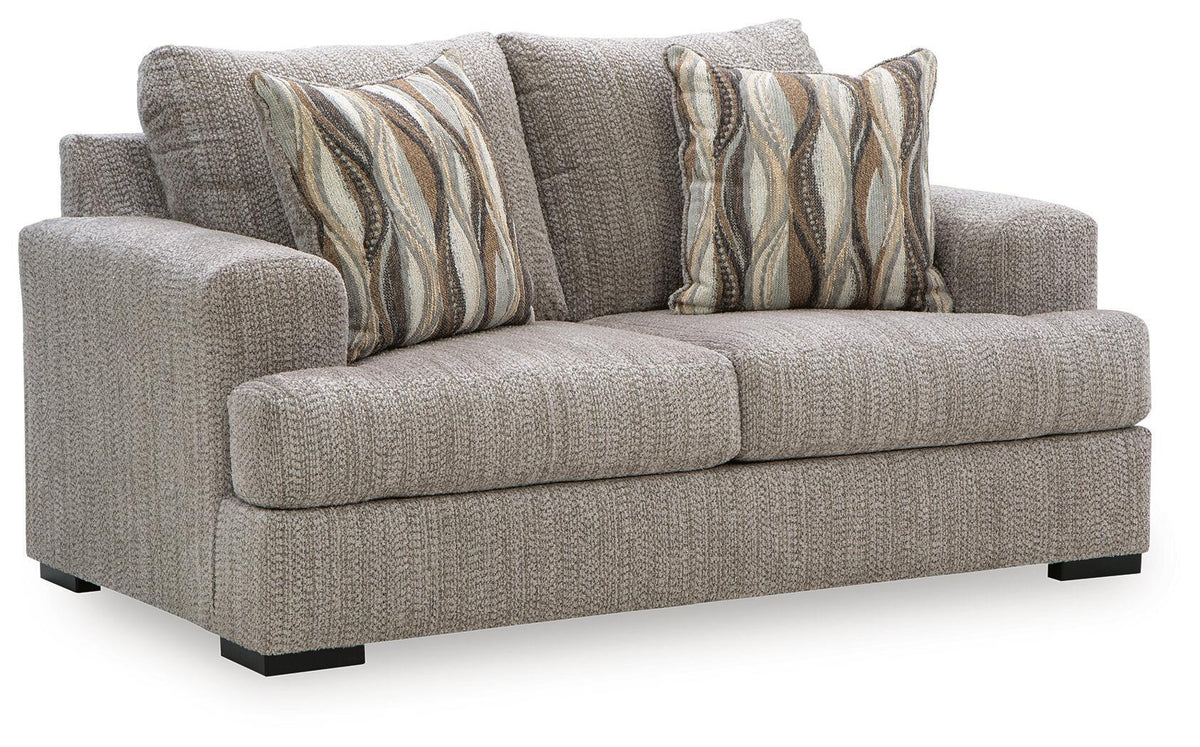 Light gray upholstered loveseat with two striped wave throw pillows