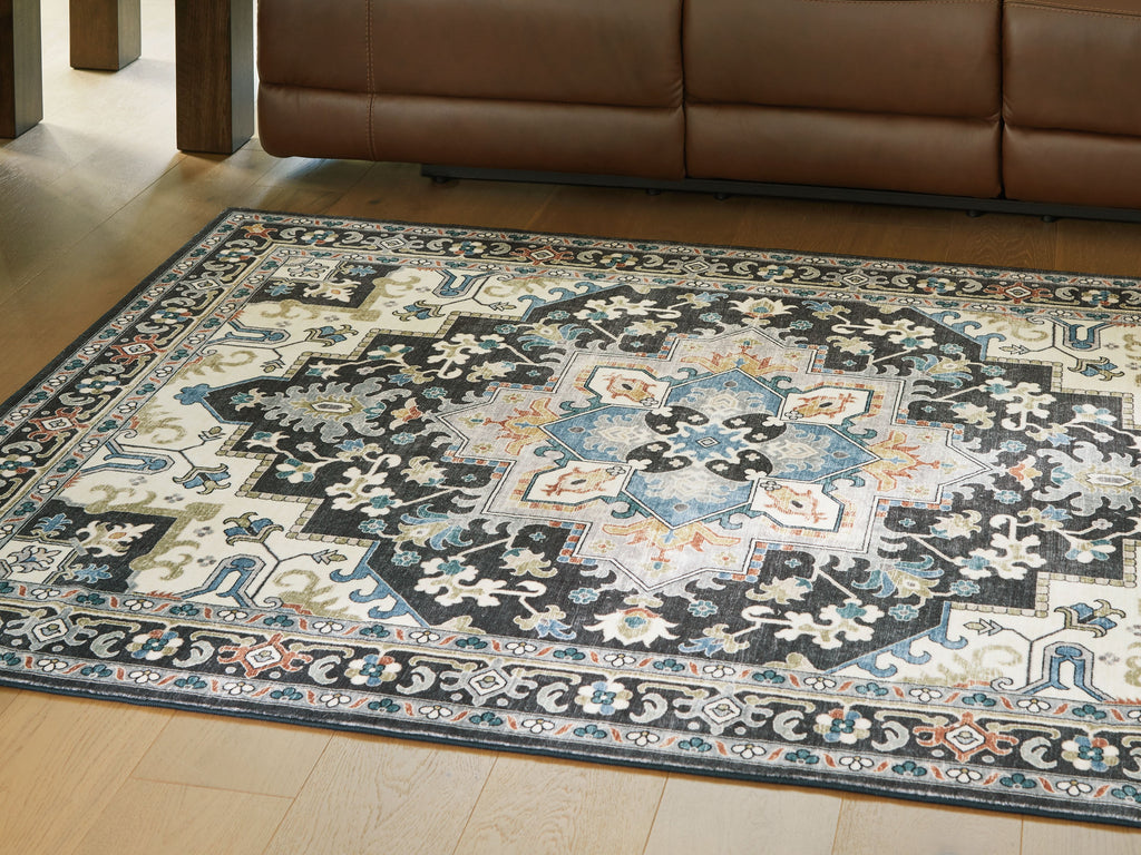 Washable area rug laid on wood floor, black-and-light blue ornate pattern.
