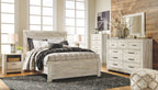 Light wood panel bed frame with black and beige quilt and pillows