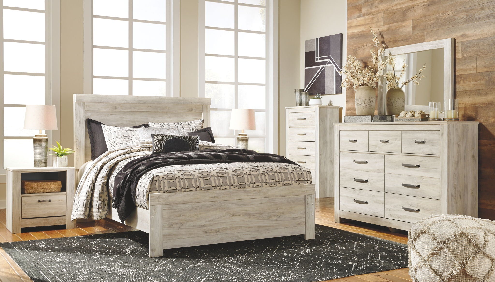 Light wood panel bed frame with black and beige quilt and pillows