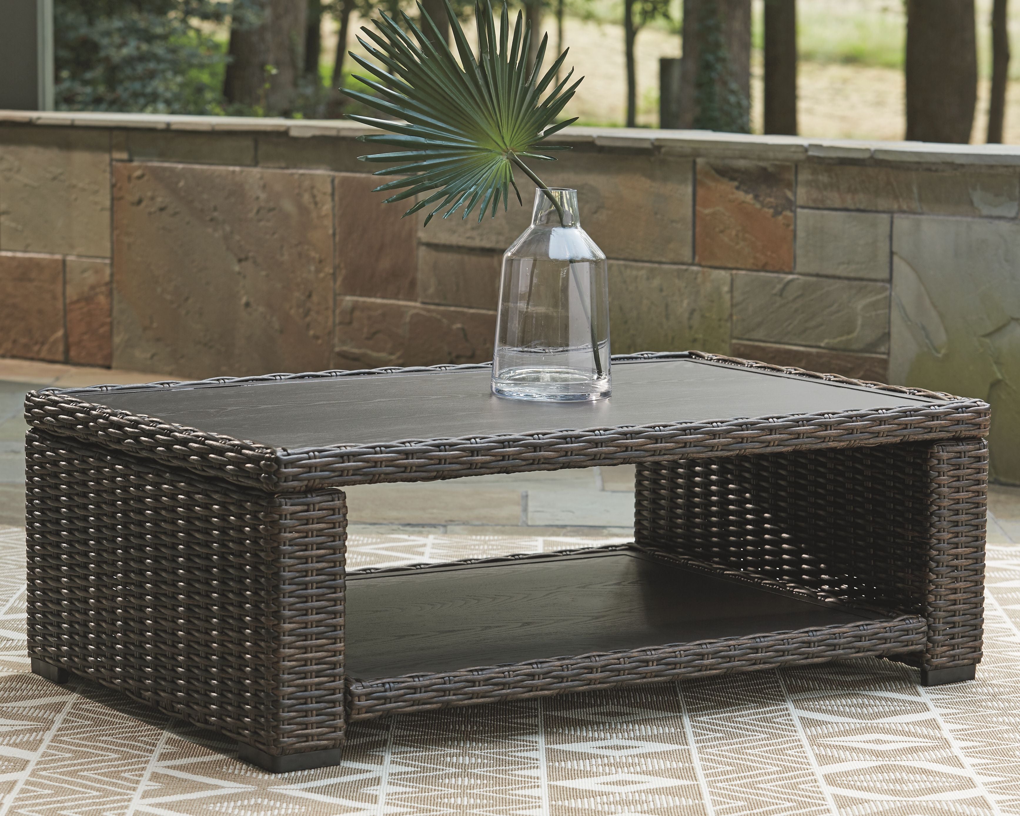 Rectangular brown wicker cocktail table with glass top and lower shelf