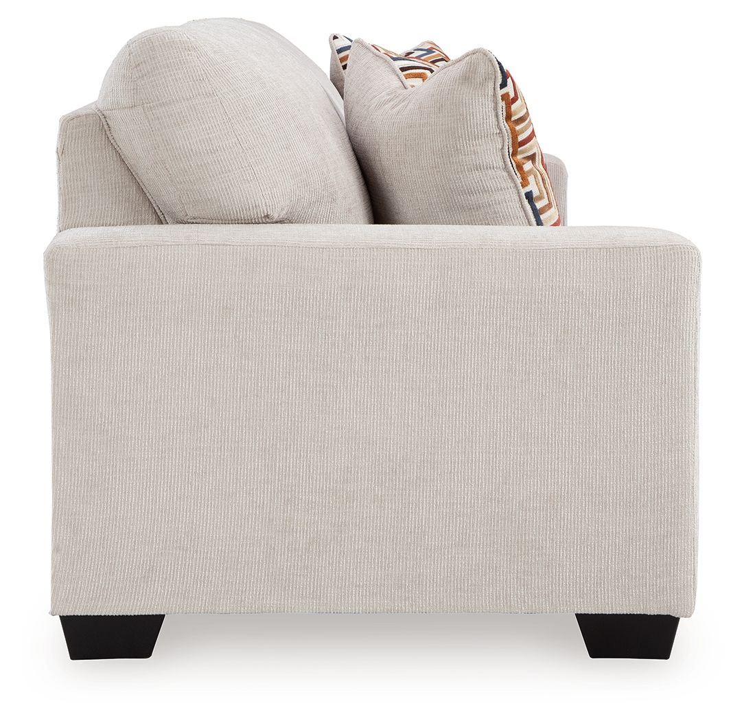 Stone sofa sleeper with armrests and two patterned throw pillows, front view.