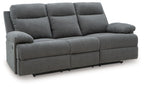 Dark gray reclining sofa with tufted back cushions and padded armrests