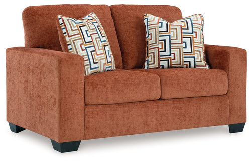 Brown loveseat with two geometric patterned throw pillows and squared arms