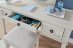 Antique white vanity drawers open with interior organizers and curved metal pulls