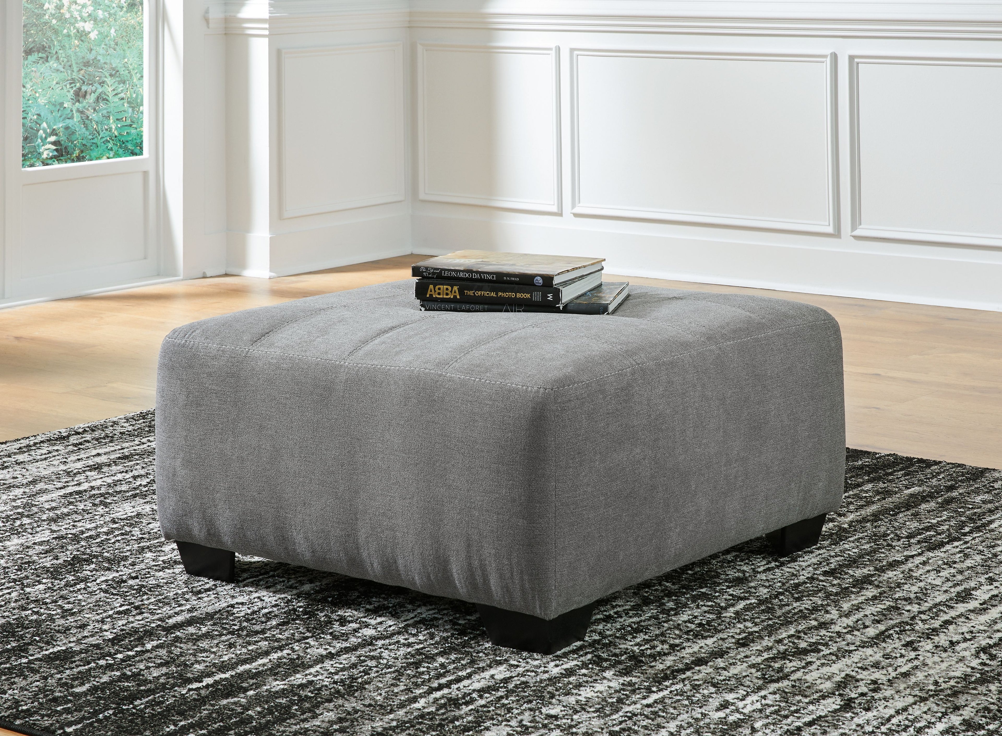 Gray oversized ottoman with thick padded seat and tapered black legs