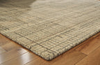 Corner of ivory, gray, tan area rug on wood floor, low flat weave