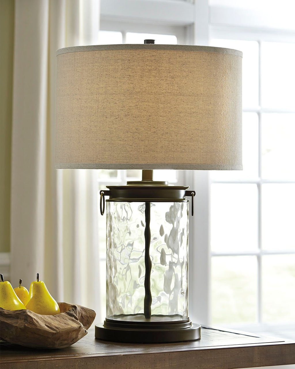 Clear glass table lamp with beige drum shade and dark bronze metal frame