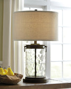 Clear glass table lamp with beige drum shade and dark bronze metal frame