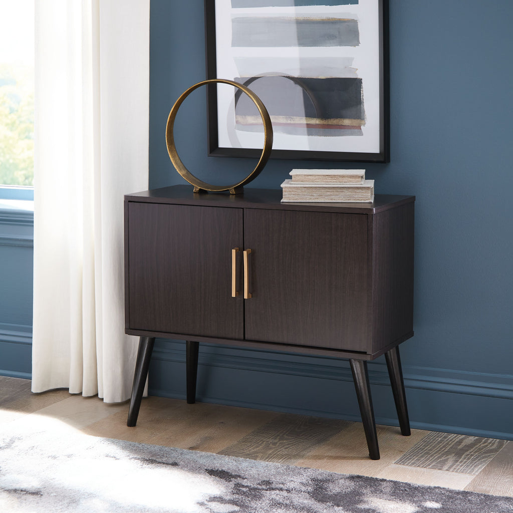 Dark wood accent cabinet with two doors and vertical gold bar handles, standing legs