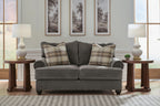 Gray upholstered loveseat with two plaid pillows and two seat cushions