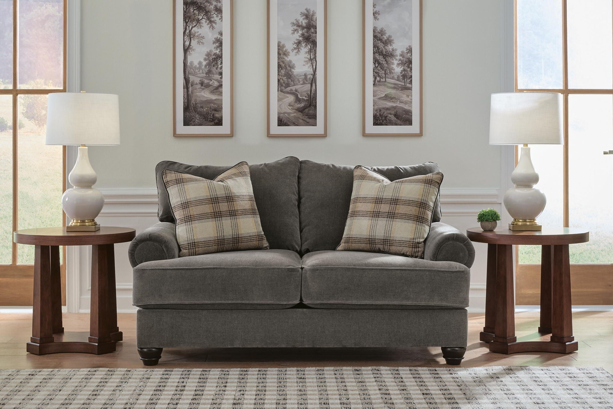 Gray upholstered loveseat with two plaid pillows and two seat cushions