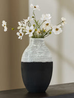 Black and white ceramic vase on tabletop with white daisy-like flowers