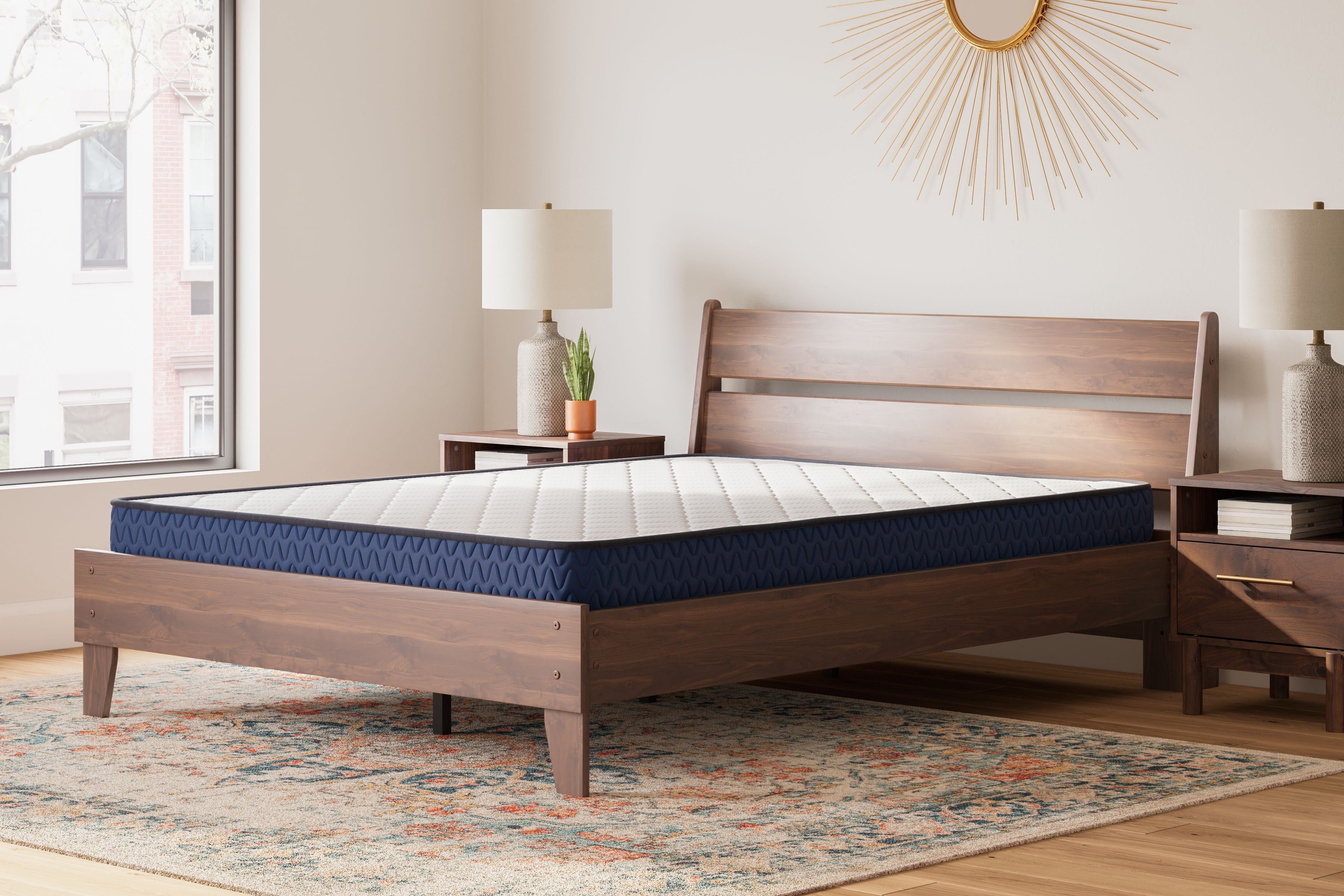 Firm mattress with white quilted surface and blue edge on a light wood bed frame