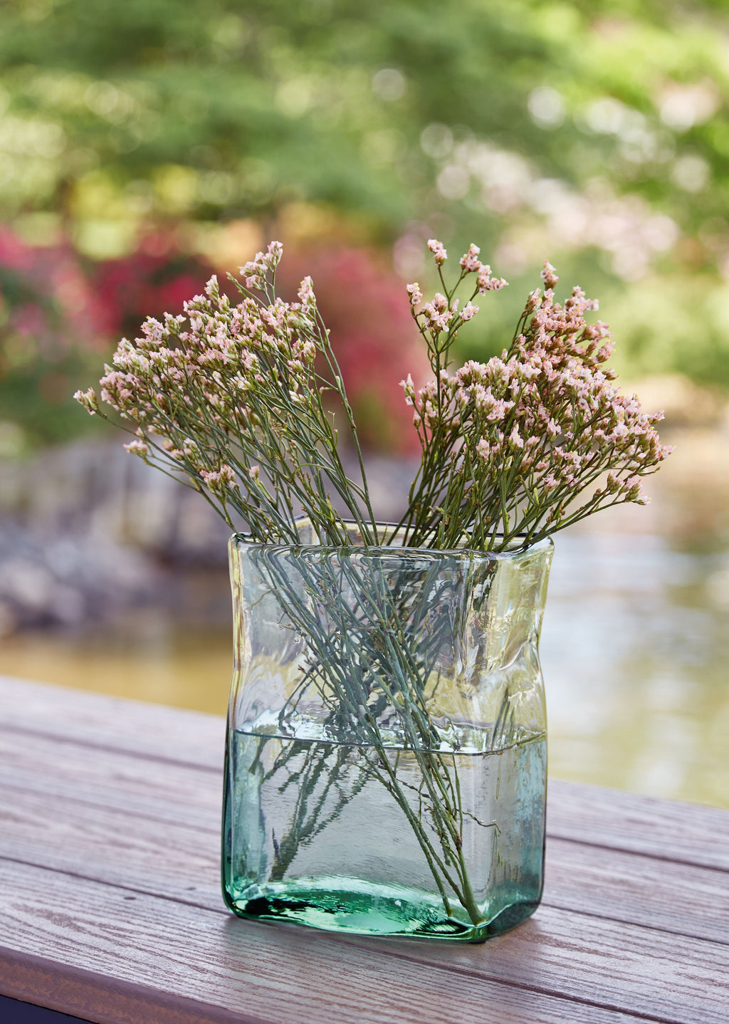 Taylow green glass vase holding stems, visible through clear body