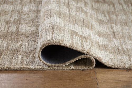Light brown area rug corner with low-pile edge and abstract woven texture