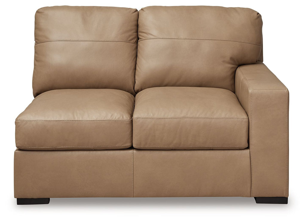 Toffee-brown leather loveseat with two front seat cushions, wide arms, and back pillows