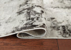 Area rug rolled edge, showing gray underside and black-and-gray distressed pattern