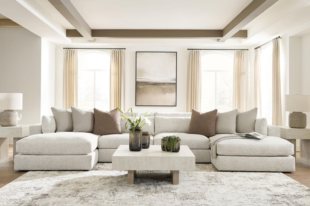 Beige sectional sofa with chaise, cushioned back and arms, styled with pillows and a coffee table