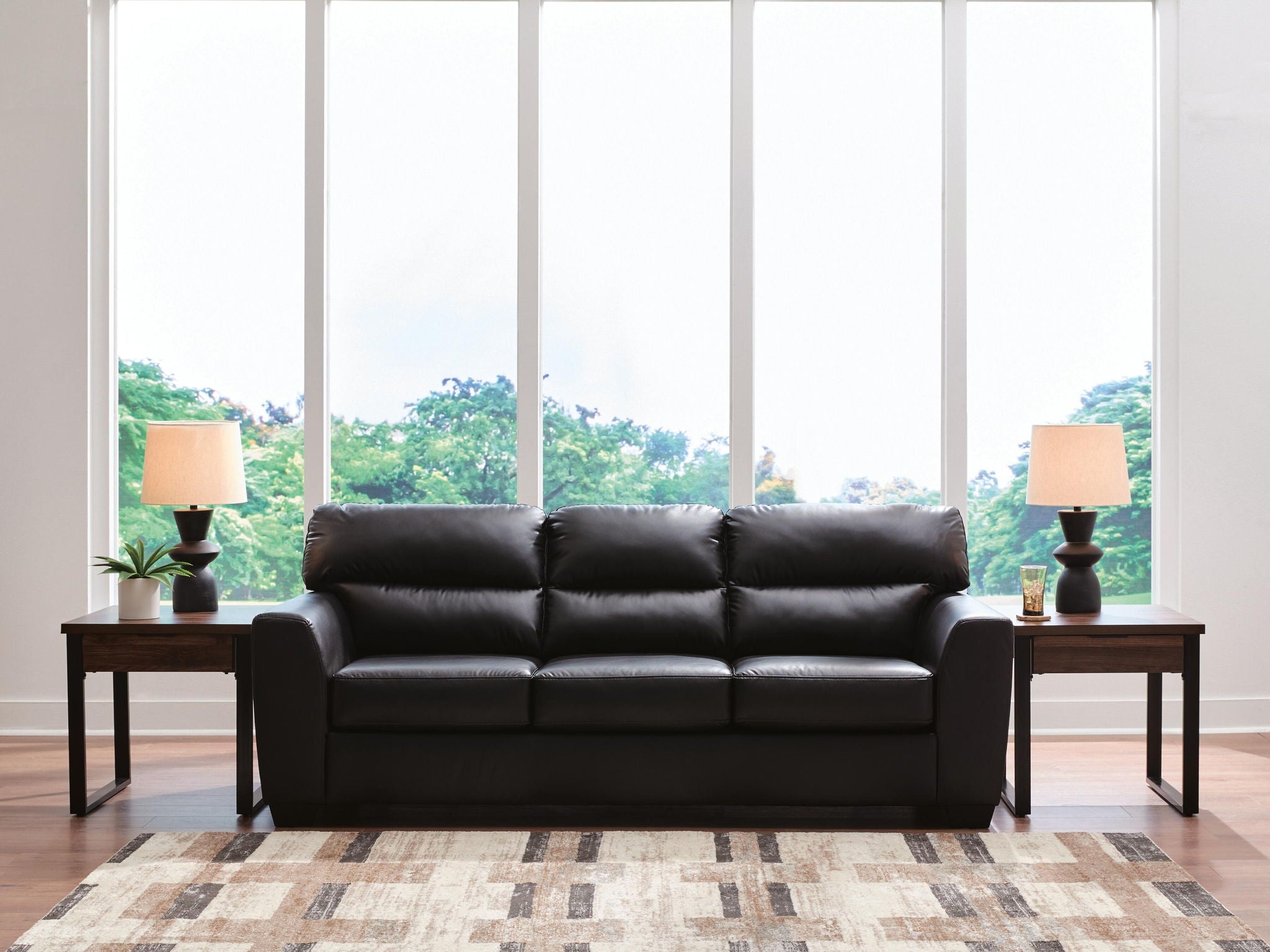Dark leather sofa with three seat cushions and tufted back, wide boxy arms