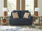 Blue reclining loveseat with two geometric patterned throw pillows