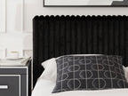Black upholstered headboard and bed frame with patterned decorative pillow and bedding.