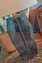 Blue faceted glass table lamp with brass neck and white drum shade, side view
