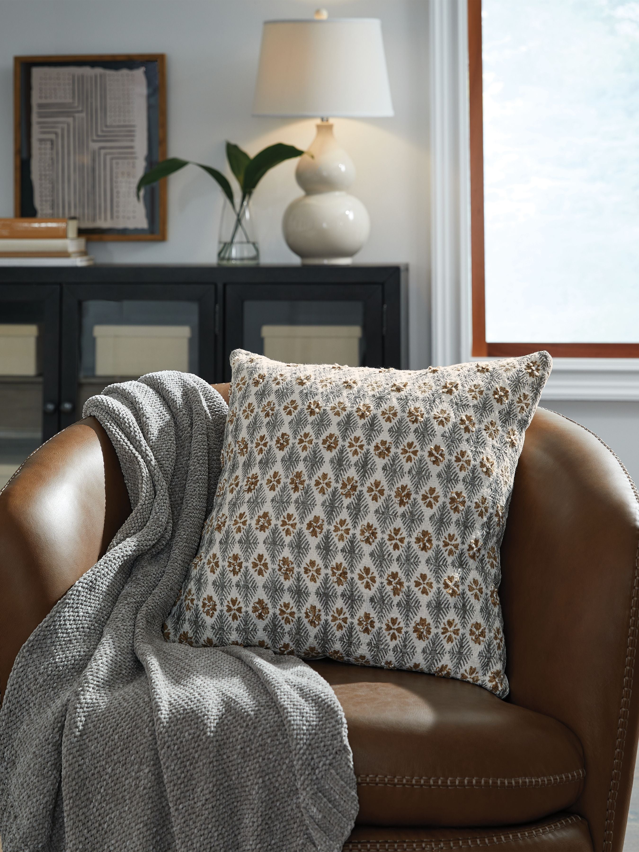 Patterned throw pillow with geometric floral print on brown sofa