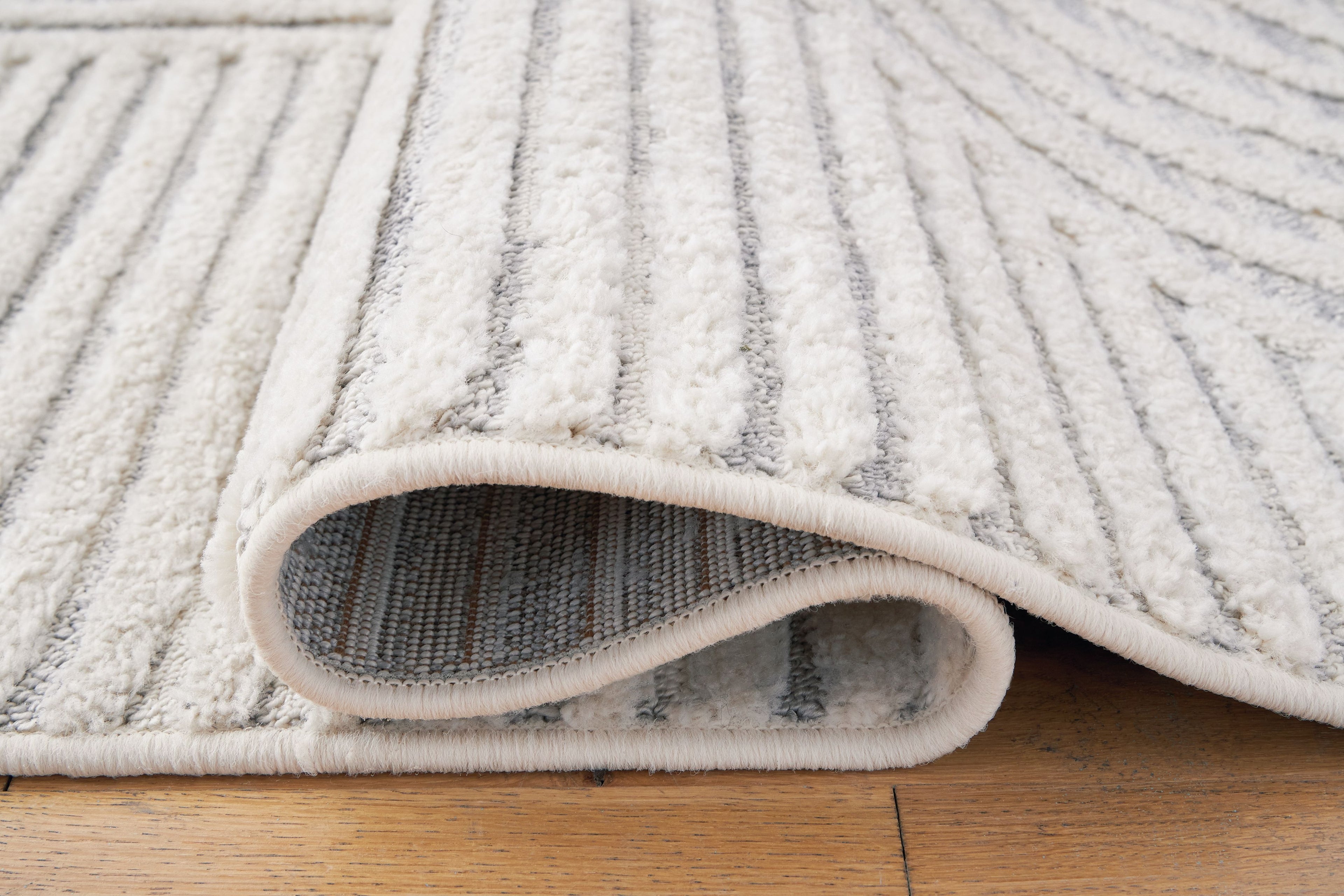 Light gray and white area rug with bound edge and ribbed pile detail