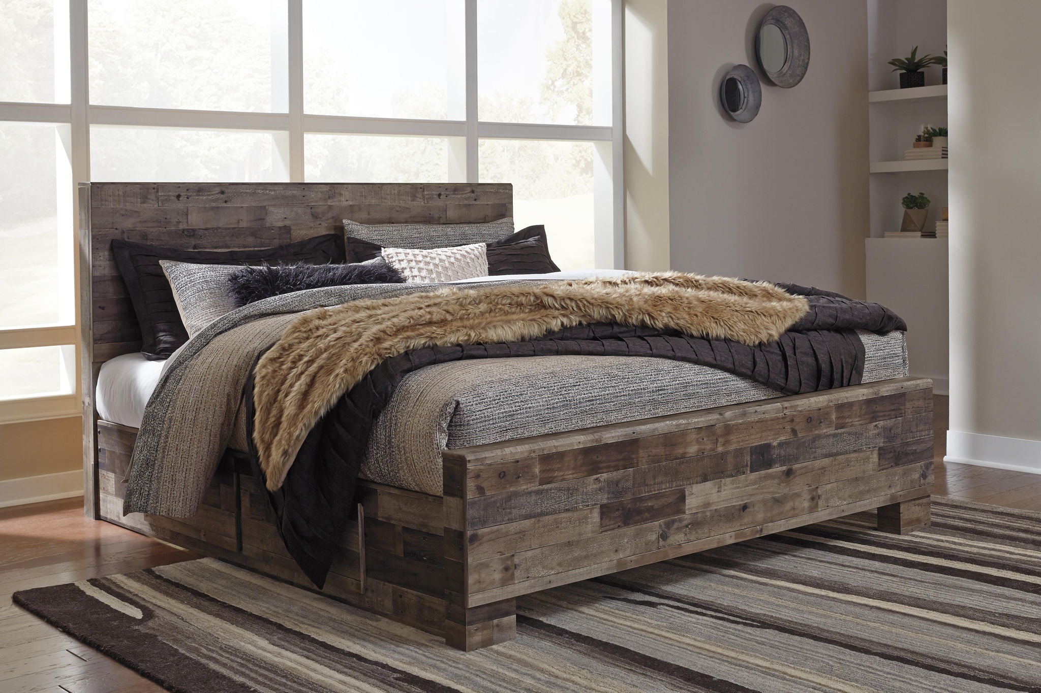 Gray upholstered panel bed with dark wood frame, pillows, and faux-fur throw