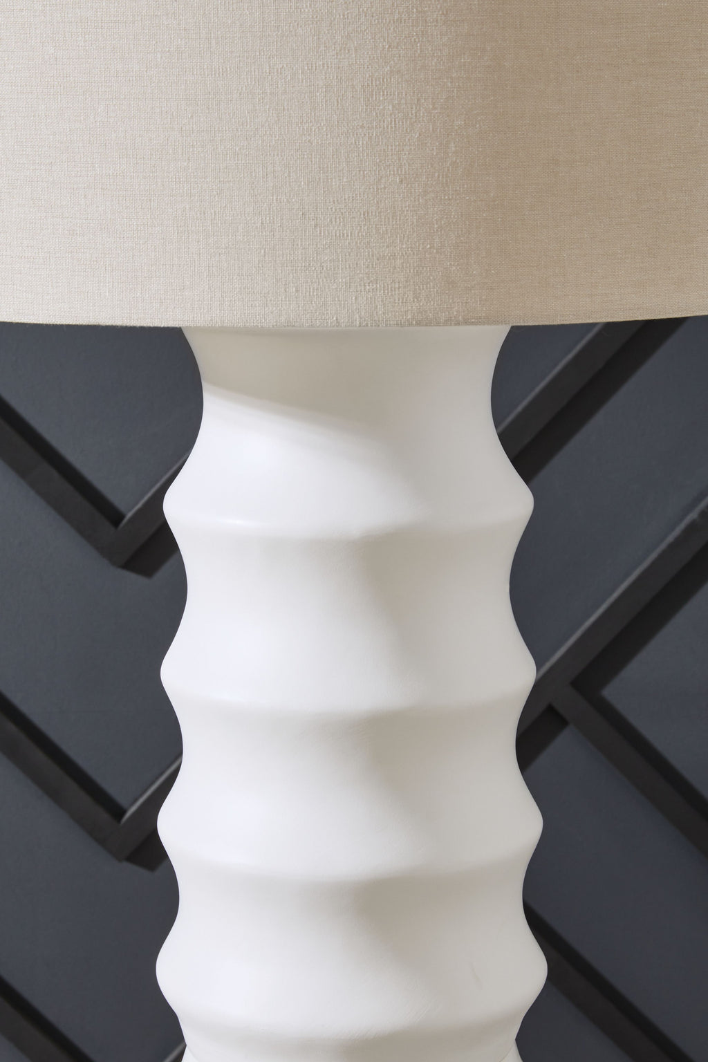 White lamp base with ridged pattern under drum shade, close-up side view