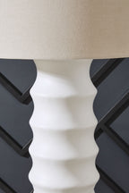 White lamp base with ridged pattern under drum shade, close-up side view